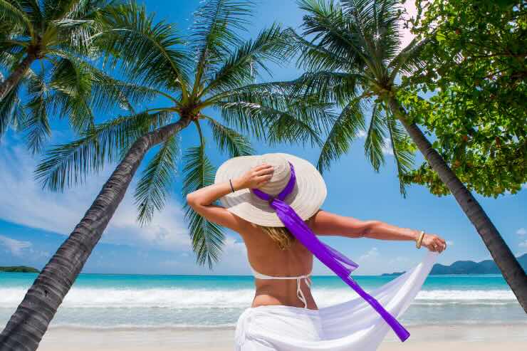 donna con cappello di spalle fra le palme